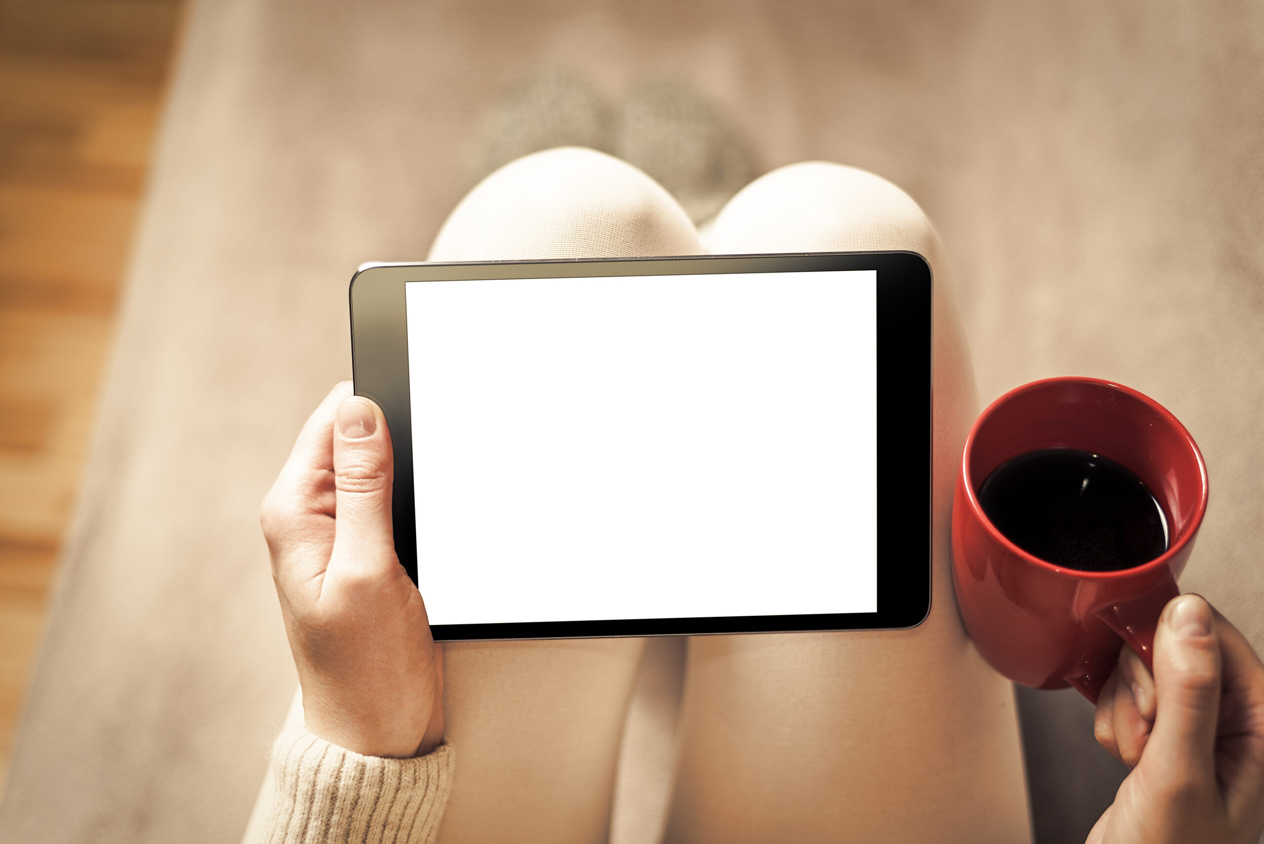Woman on the sofa with tablet and cup of coffee in hands. Toned photo.